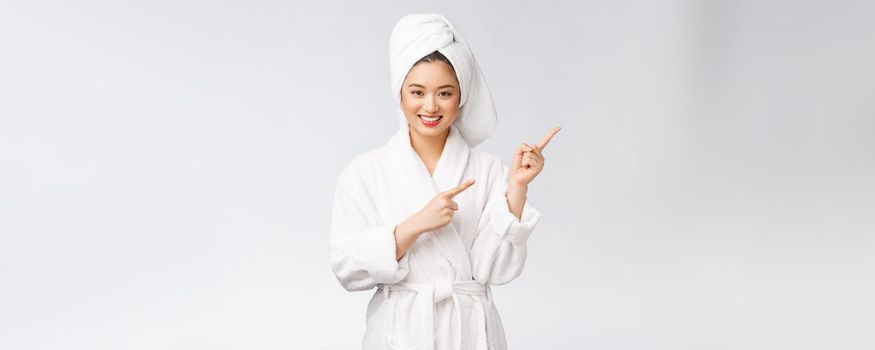 Beauty portrait of young woman showing and pointing finger to empty copy space, asian beauty in bathrobe.