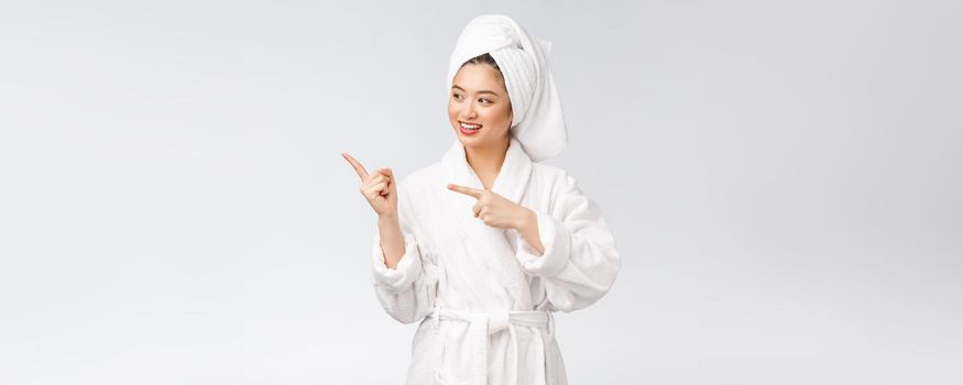 Beauty portrait of young woman showing and pointing finger to empty copy space, asian beauty in bathrobe.
