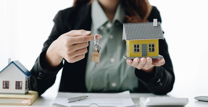 Estate agent are presenting home loan and sending keys to client after signing contract to rental house Insurance with approved property form.