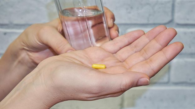 Women's hands hold one pill