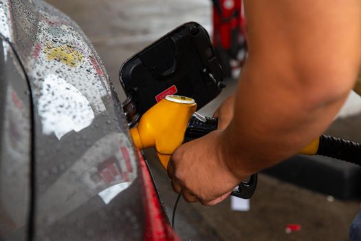 Man filling gasoline fuel in car holding pump.