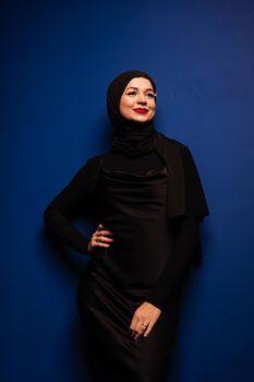 Fashion muslim model in black hijab is posing on blue background in studio. Islam religion.