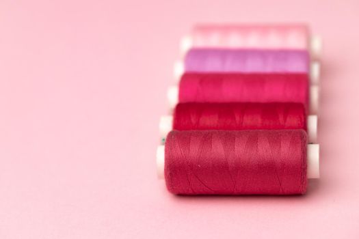 Set of threads spools on pink background