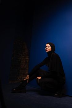 Fashion muslim model in black hijab is posing on blue background in studio. Islam religion creative photo