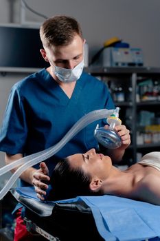 Anesthesiologist making ingalation anesthesia for patient. Doctor puts a mask on the patient before starting operation