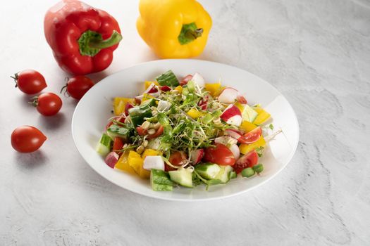 Wheat germ salad, tomatoes, peppers, radish, cucumber, olive oil. Vegetable salad on white plate on gray background.
