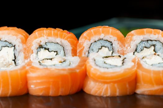 Philadelphia rolls with salmon, cream cheese, cucumber, avocado, nori close-up. Traditional Japanese cuisine
