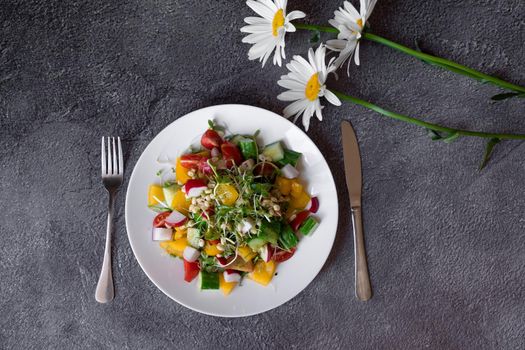 Wheat germ salad, tomatoes, peppers, radish, cucumber, olive oil. Vegetable salad on white plate on gray background.