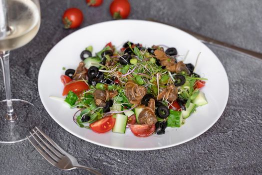 Salad with snail, olive, tomatoe cherie, cucumber, greens on dark background.