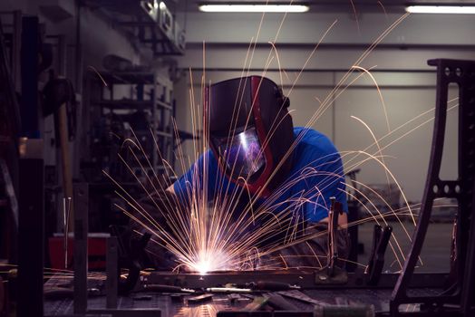 Professional Heavy Industry Welder Working Inside factory, Wears Helmet and Starts Welding. Selective Focus