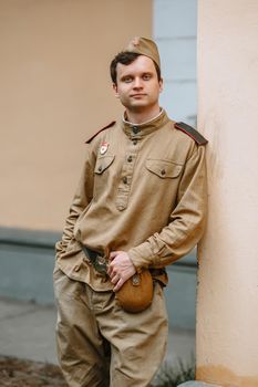 A man in a Soviet world war II uniform stands at the yellow wall