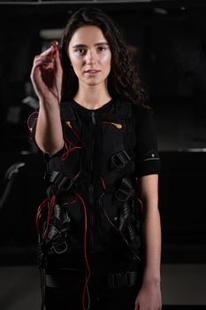 Girl with electronic contactor of EMS suit in gym. Sport training in electrical muscle stimulation suit.