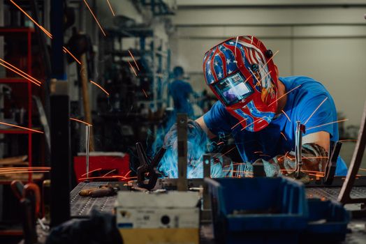 Professional Heavy Industry Welder Working Inside factory, Wears Helmet and Starts Welding. Selective Focus