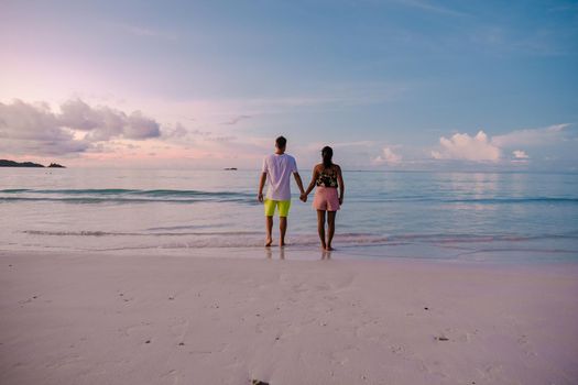 Praslin Seychelles tropical island with withe beaches and palm trees, couple men and women mid age on vacation at the Seychelles watching sunset at the ocean