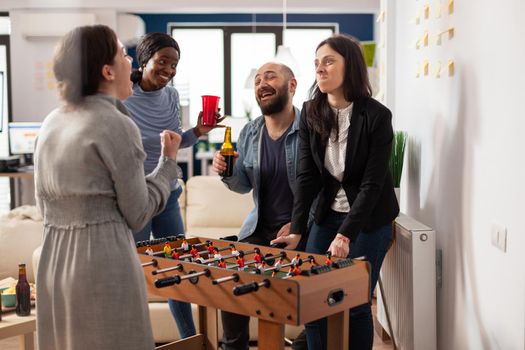 Diverse group of colleagues having fun with foosball table game
