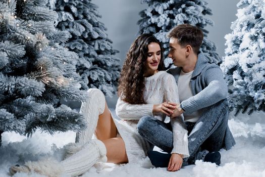 New year love story. Couple kiss and hug. Happy young couple near christmas trees in winter day