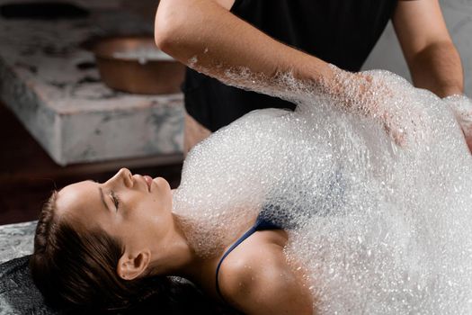 Turkish hammam spa procedure. Foam peeling massage for body.