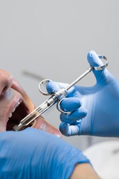 Dentist injects anesthesia syringe of the diseased teeth for the patient. Caries treatment.