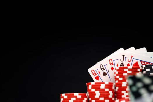 Poker chips and playing cards on black background