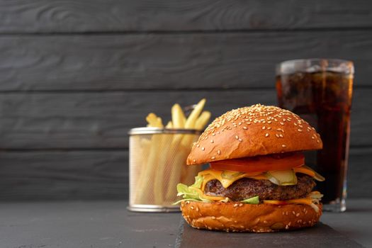 Fresh burger and fries on black wooden background