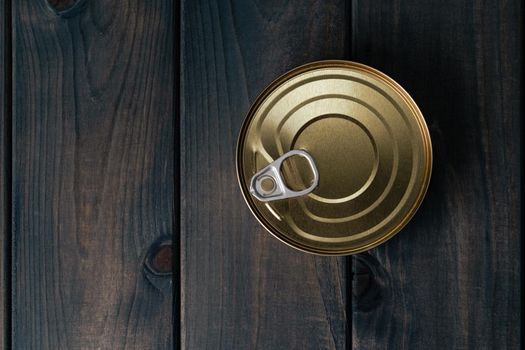 One tin with canned food on black wooden background