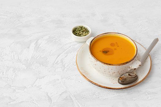 Blended pumpkin soup in bowl on gray background