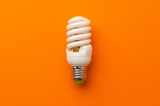 Light bulb on bright orange background top view