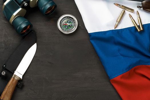 Hunting knife, binoculars and cartridges with russian flag on black background