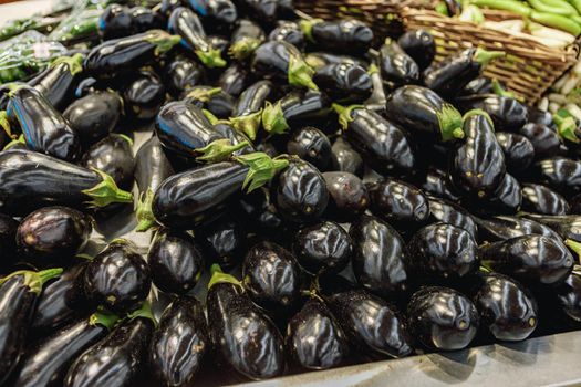 Pile of eggplant for sale on counter in supermarket