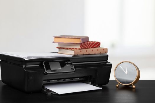 Stack of books and home printer against blurred background
