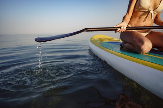 Close up of young woman sitting on a stand up paddle board