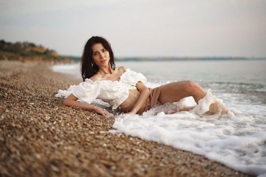 Young relaxed woman sitting all alone on empty beach