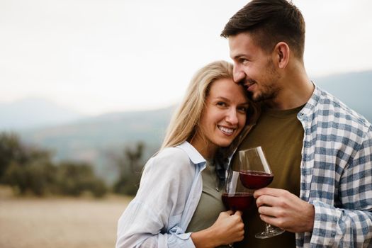 Smiling couple toasting wine glasses outdoors in mountains