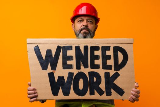 Sad senior builder is looking for work against orange background