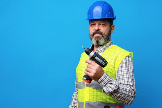 Constructor handyman in blue hardhat holding screwdriver against blue background