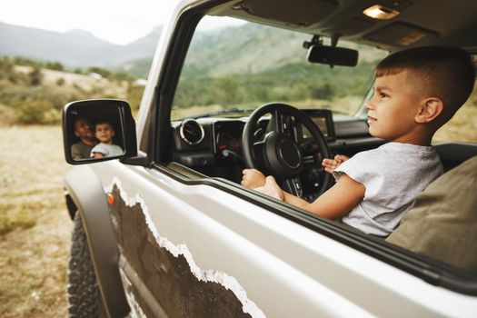 Father teaches little son to drive on road trip
