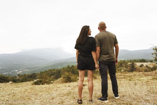 Back view of couple standing and looking at foggy mountains