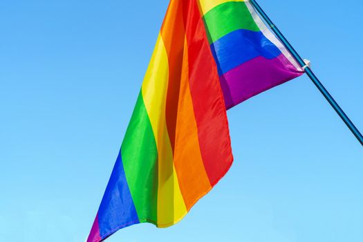 LGBT waving flag in the sky on flagpole