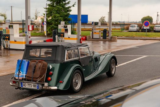 Paris, France-June,10 2021: Green retro car with luggage. Petrol station. Fuel business