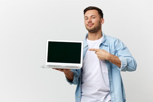 Cheerful friendly tanned handsome IT professional man in casual basic t-shirt point finger at laptop posing isolated on white studio background. Copy space Banner Mockup. Electronics repair concept