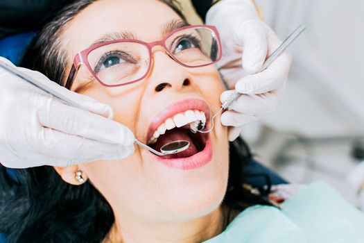 Patient checked by dentist, close up of dentist with patient, dentist performing root canal treatment on patient, dentist performing dental checkup