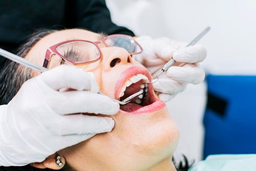 Female dentist checking a patient, close up of dentist with patient, dentist performing root canal on patient, dentist performing dental checkup