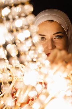 Fashion muslim model near big expensive chandelier. Islamic religion.