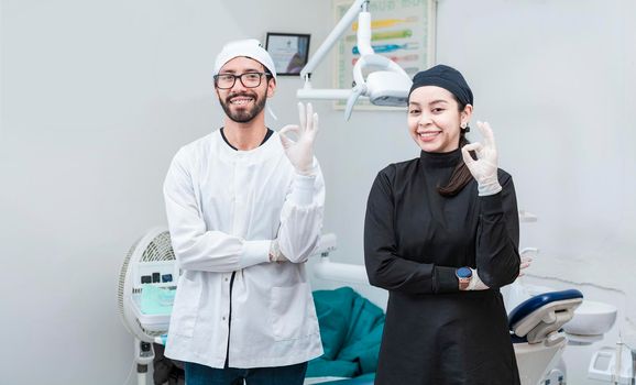 Portrait of dentist and her assistant in the office, female dentist and her assistant thumbs up, oral professionals portrait