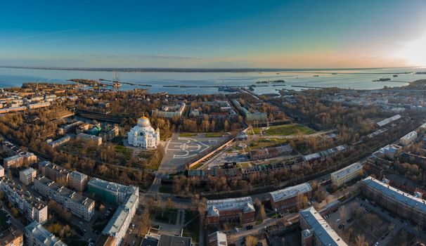 Aerial view of the sea capital of Russia Kronstadt at sunset, the golden dome of the huge main naval cathedral of St. Nicholas, the seaport with warships, dry docks, fortifications with cranes