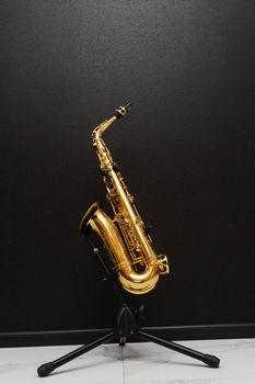 Sax musical instrument for play jazz. Saxophone musician instrument on stand on black background.