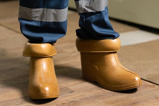 Electrician wears rubber boots for safety to avoid electric shock. Concept of electric power station development. Electrical technician is putting on special protective shoes in power station