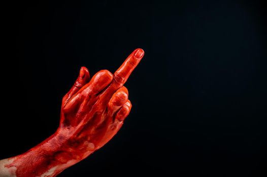 Female hand stained with blood shows the middle finger on a black background.