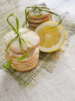 Pile of lemon sugar cookies tied up with rope on linen tablecloth, blurred background