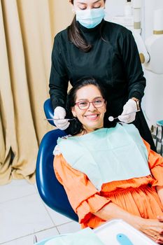 Dentist examining mouth to smiling patient, Female dentist doing root canal to female patient, Female dentist with lying patient, Dentist performing stomatology